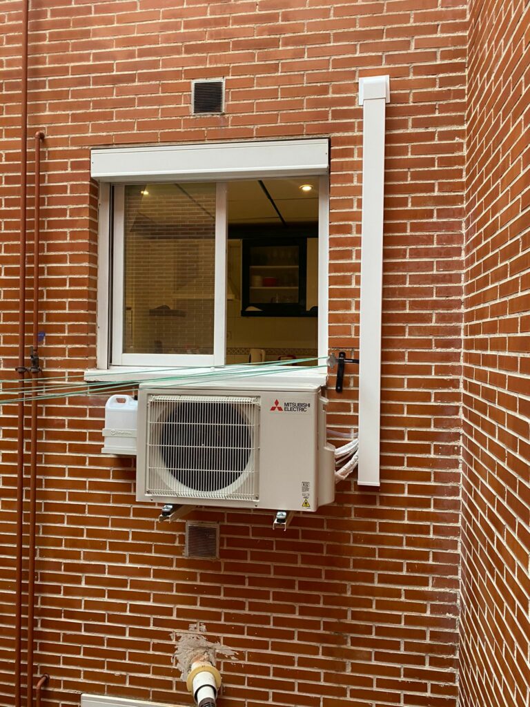 Unidad de compresor para aire acondicionado tipo pared instalada en el  exterior del edificio.